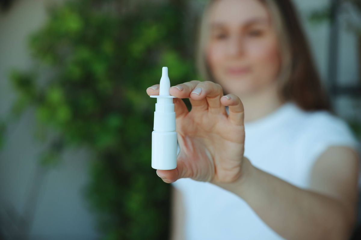Woman is having flu and she is using nasal spray to help herself. Woman using nasal spray. Nasal spray to help a cold. Sick with a rhinitis woman dripping nose. Woman applies nasal spray