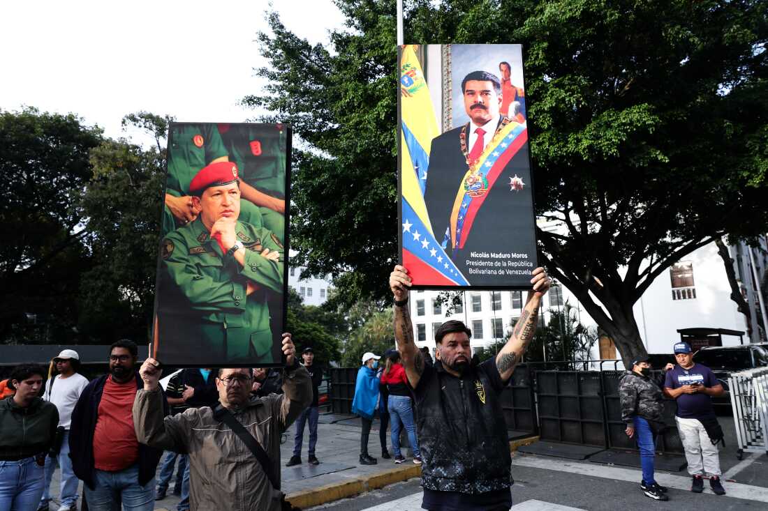Supporters of Venezuela's current and former president, Nicolas Maduro and the late Hugo Chavez, hold posters with their images in Caracas on Saturday.