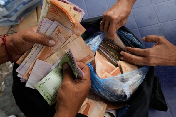 People exchange U.S. dollars for Venezuelan bolivars at a street market in Caracas, Venezuela, Thursday, Jan. 8, 2026. (AP Photo/Matias Delacroix)
