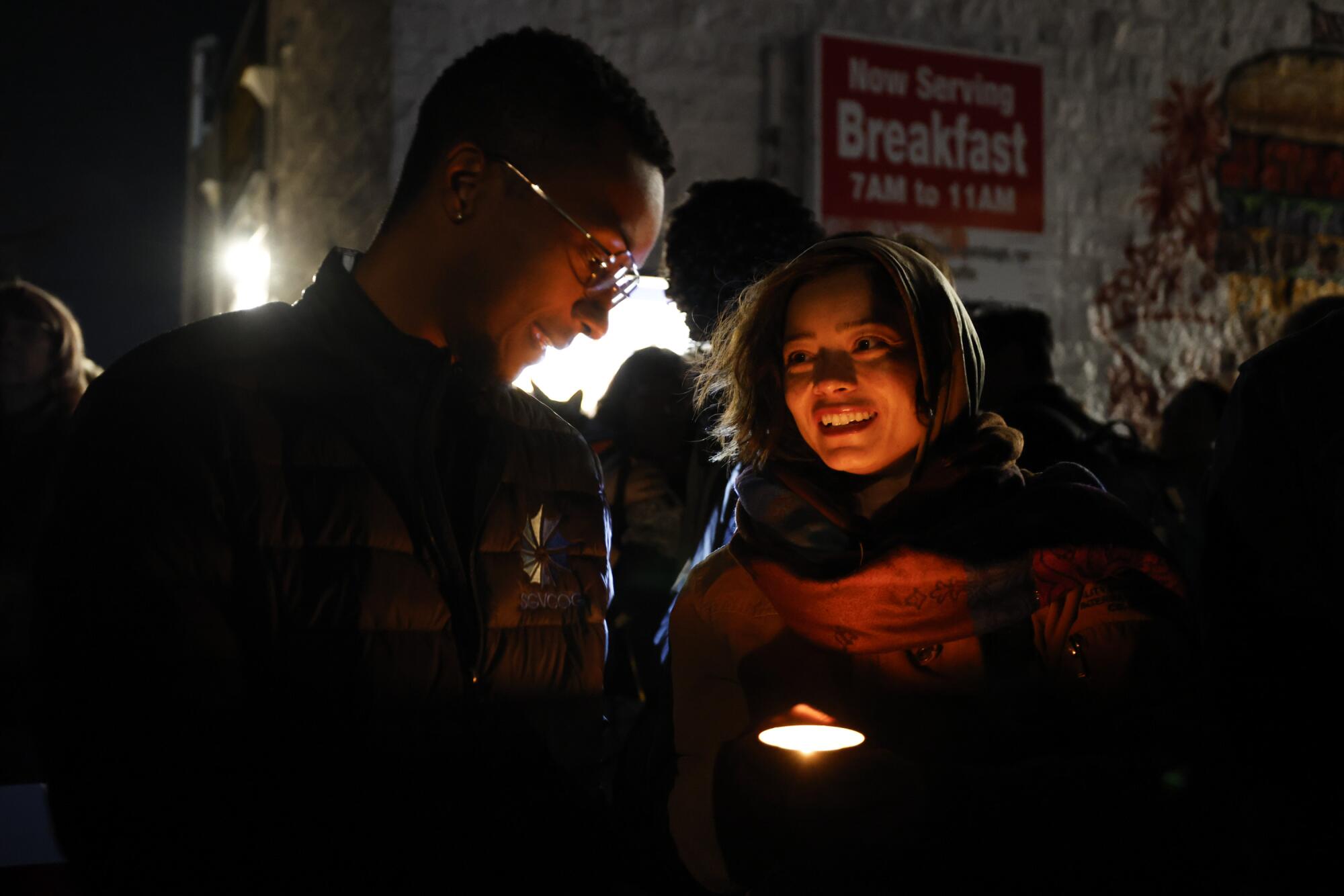 Two people smile as one of them holds a candle.