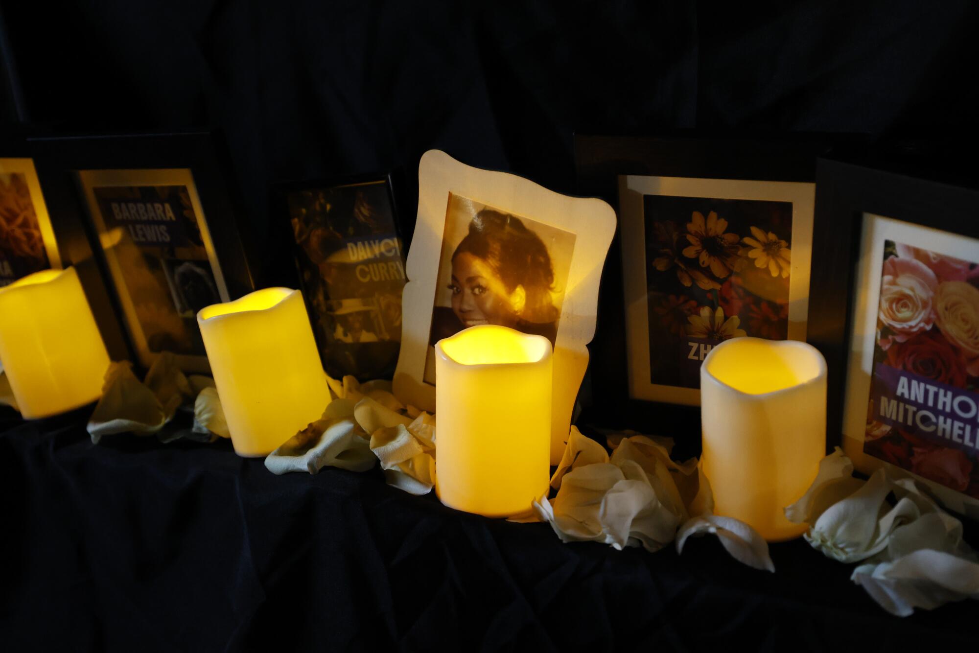 Photographs are positioned behind a row of candles and flower petals.