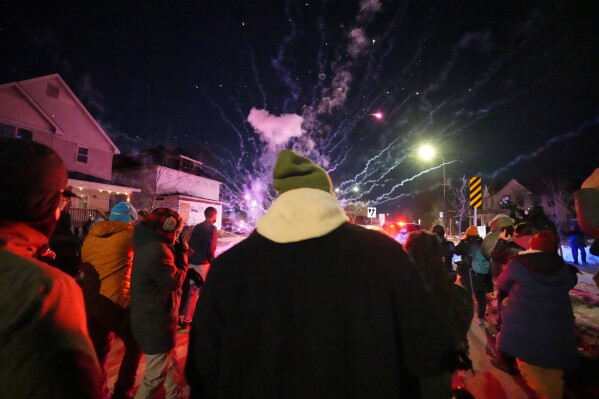 People react after a firework was set off near the scene of a reported shooting Wednesday, Jan. 14, 2026, in Minneapolis. (AP Photo/Abbie Parr)