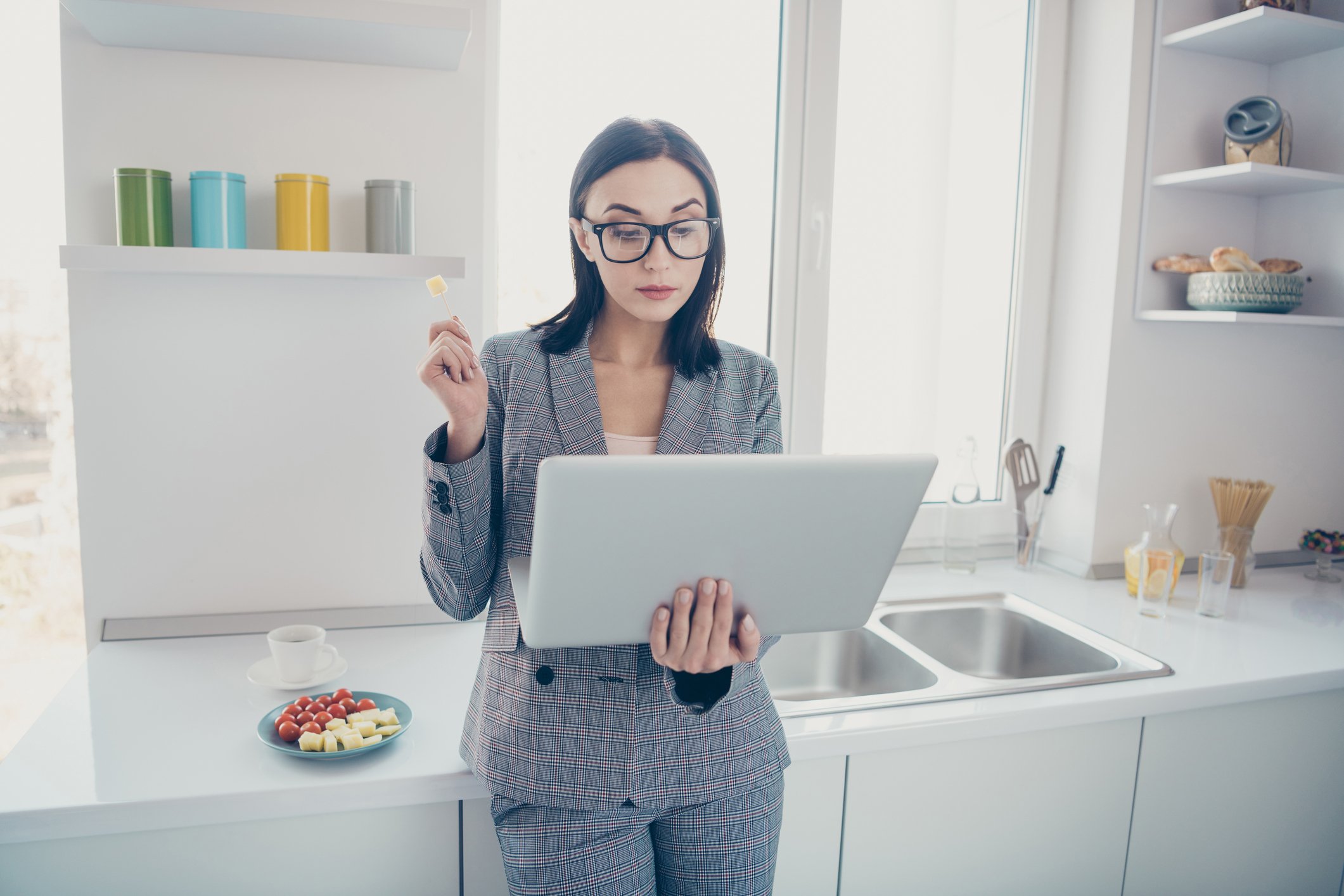 A person in a kitchen looks at a laptop.