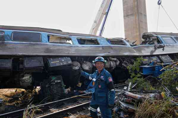 A rescuer stands near the wreckage after a construction crane fell into a passenger train in Nakhon Ratchasima province, Thailand, Wednesday, Jan.14, 2026. (AP Photo/Sakchai Lalit)
