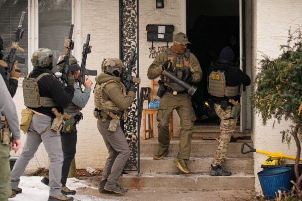 Federal immigration officers prepare to enter a home to make an arrest after an officer used a battering ram to break down a door Sunday, Jan. 11, 2026, in Minneapolis. (AP Photo/John Locher)