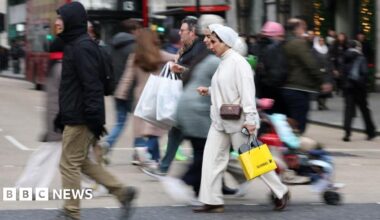 People walk with shopping bags on Oxford Street during Boxing Day sales, in London.