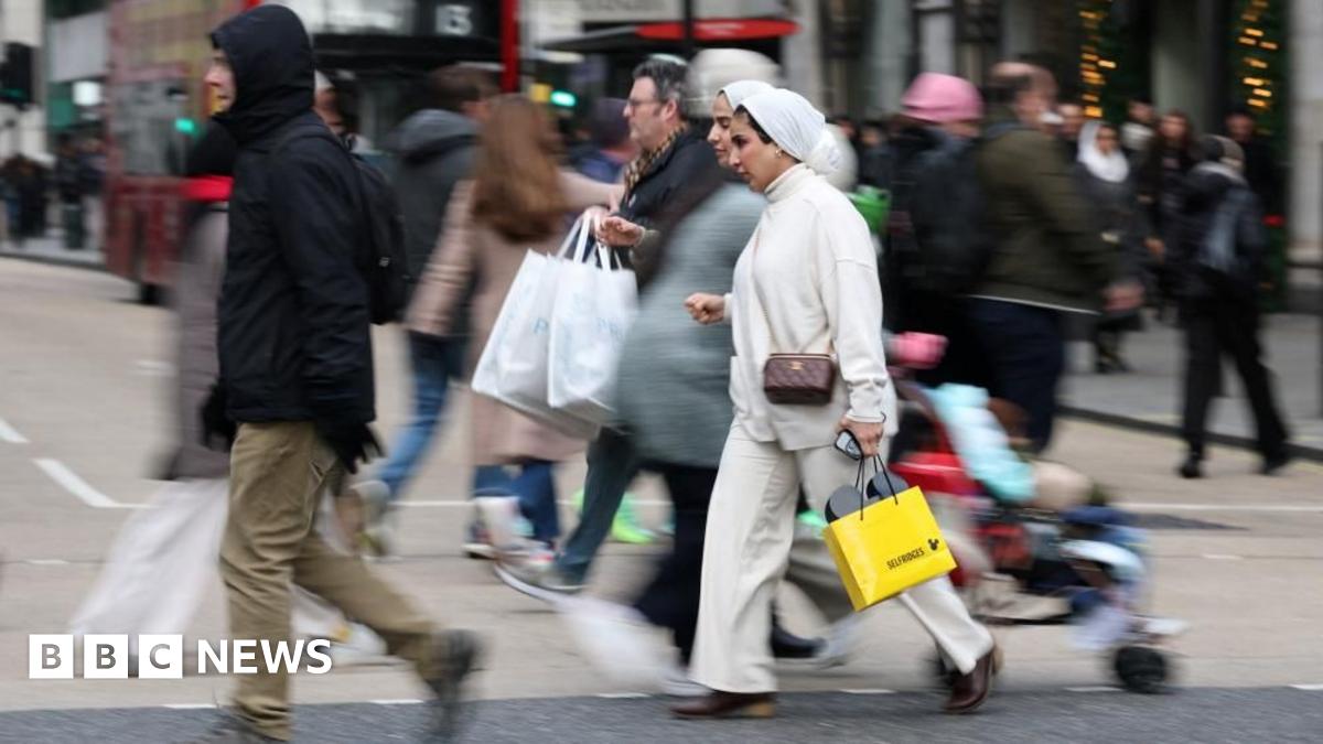 People walk with shopping bags on Oxford Street during Boxing Day sales, in London.