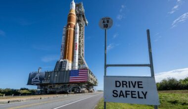 Artemis II SLS heading to the launch pad with "Drive Safely" sign in the foreground