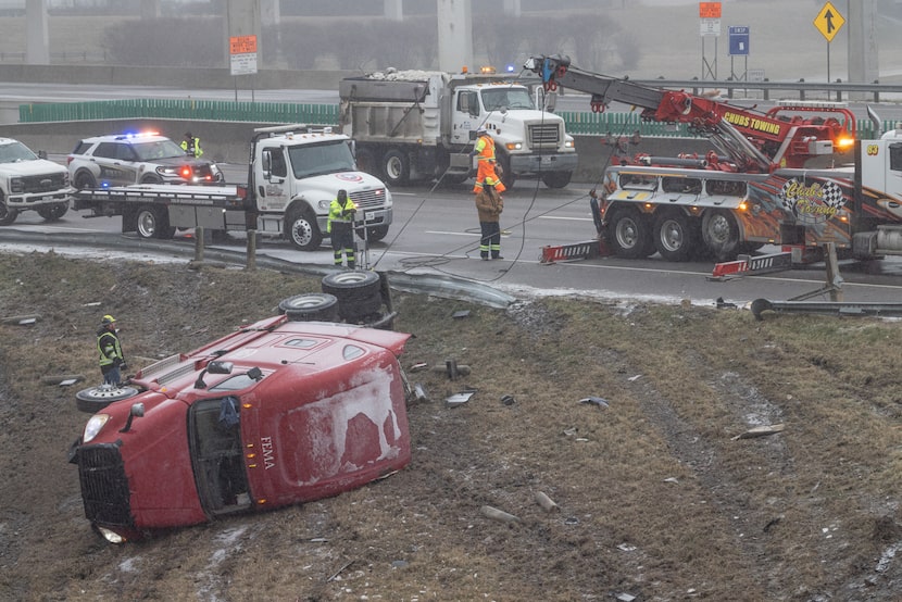 Tow truck crews pull wrecked semi-trucks out of a ditch along Interstate 20 near the...