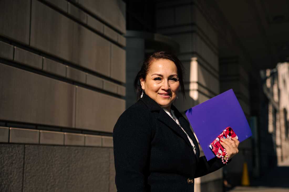 Zaida Meza, of Guatemala, holds a folder and her phone. Her nails are painted red, white and blue. 
