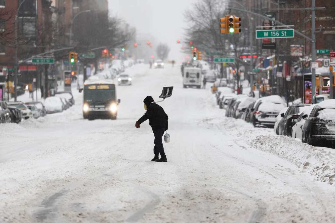 A man carries a shovel as he crosses a street in the Hamilton Heights neighborhood in New York on Sunday.