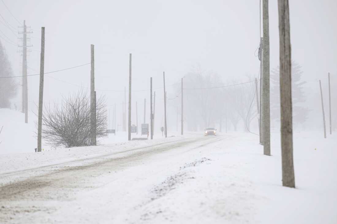 A vehicle drives through snowy conditions on Sunday in Louisville, Ky.