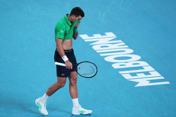 Novak Djokovic of Serbia wipes the sweat from his face during his first round match against Pedro Martinez of Spain at the Australian Open tennis championship in Melbourne, Australia, Monday, Jan. 19, 2026. (AP Photo/Aaron Favila)