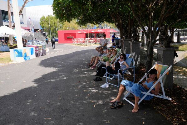 Fans sit in the shade as they watch quarterfinal matches on a video screen at the Australian Open tennis championship in Melbourne, Australia, Tuesday, Jan. 27, 2026. (AP Photo/Dar Yasin)