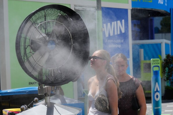 Fans cool down in front of water misters at the Australian Open tennis championship in Melbourne, Australia, Tuesday, Jan. 27, 2026. (AP Photo/Dar Yasin)