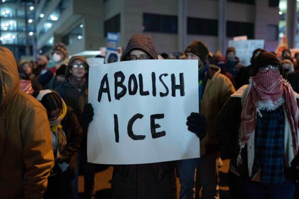 A demonstrator holds a sign during a rally outside of U.S. Immigration and Customs Enforcement headquarters in Washington, Saturday, Jan. 24, 2026. (AP Photo/Jose Luis Magana)