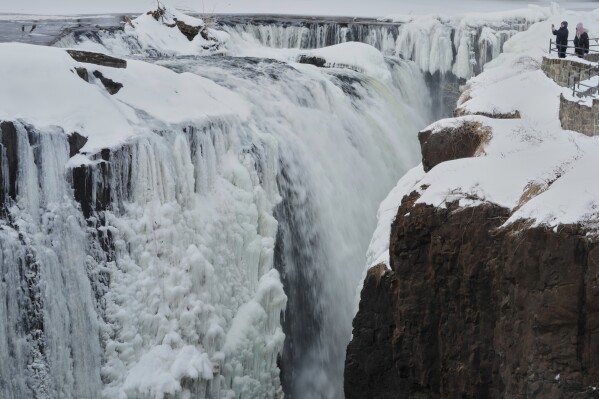 People look over the partial frozen Great Falls in Paterson, N.J., Wednesday, Jan. 28, 2026. (AP Photo/Seth Wenig, File)