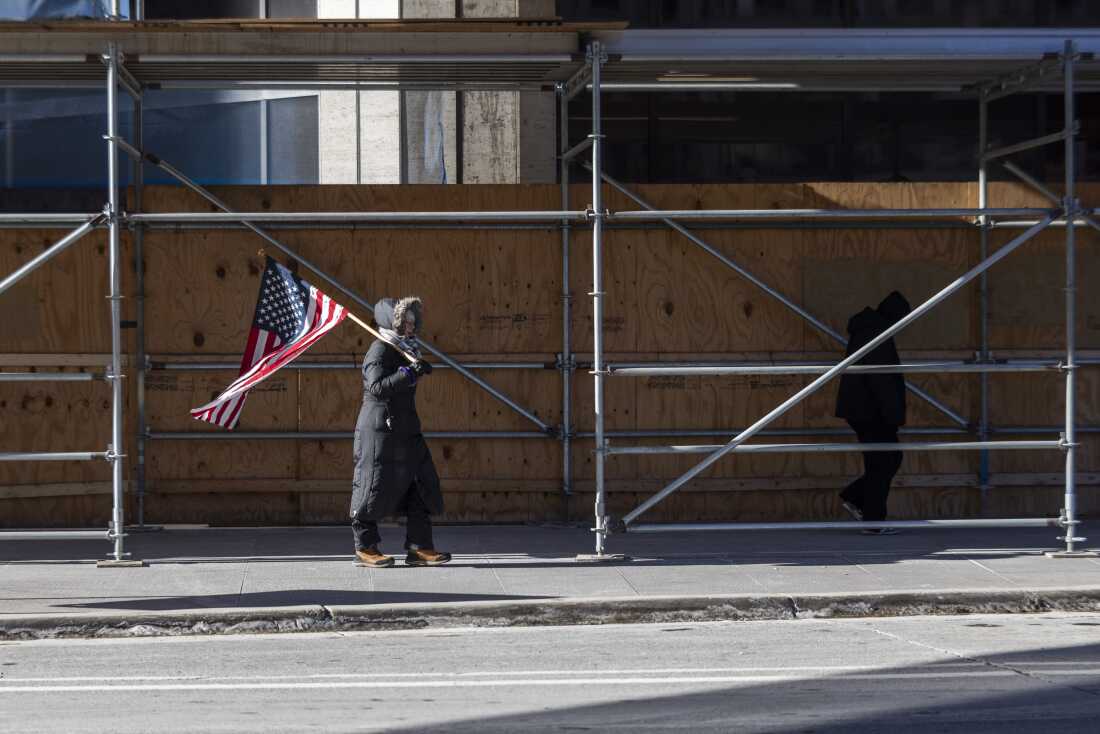 A lone person holding a U.S. flag walks through downtown Minneapolis on Friday.