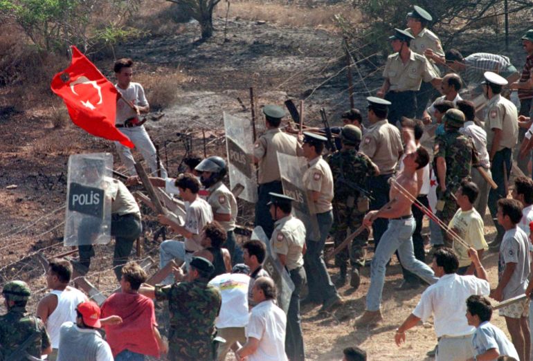 Turkish Cypriots, using slings, hurl stones against Greek Cypriots entering in the buffer zone in Derinya while the Turkish Cypriot police using shields try to stop them during a clash between Turkish and Greek Cypriots, August 11. A Greek Cypriot man was killed and 41 people wounded in clashes with Turkish Cypriots across the ceasefire line that has divided the island since Turkey invaded the north in 1974.