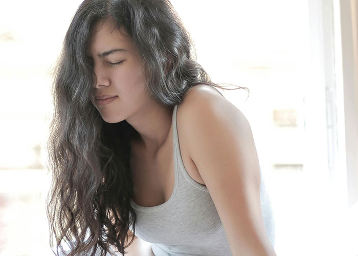 Young woman in gray tank top showing discomfort, illustrating unprofessional things doctors have said to patients.