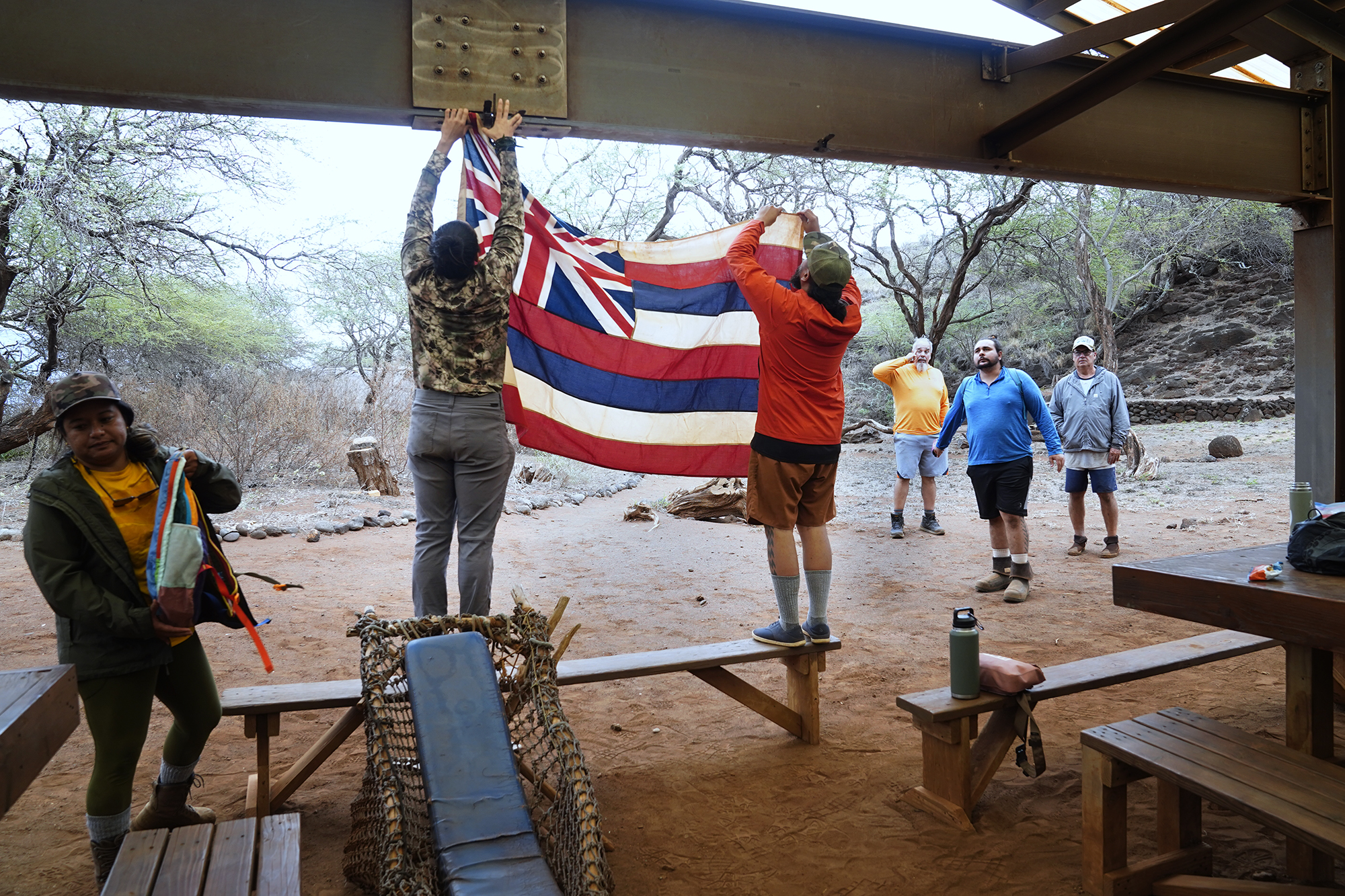 Protect Kahoʻolawe ʻOhana (PKO) Kaulu Lu‘uwai, left, and Kainoa Pestana hang the Hawaiʻi state flag Monday, Jan. 5, 2026, in Hakioawa. PKO celebrates the 50th year of sovereign land. (Kevin Fujii/Civil Beat/2026)