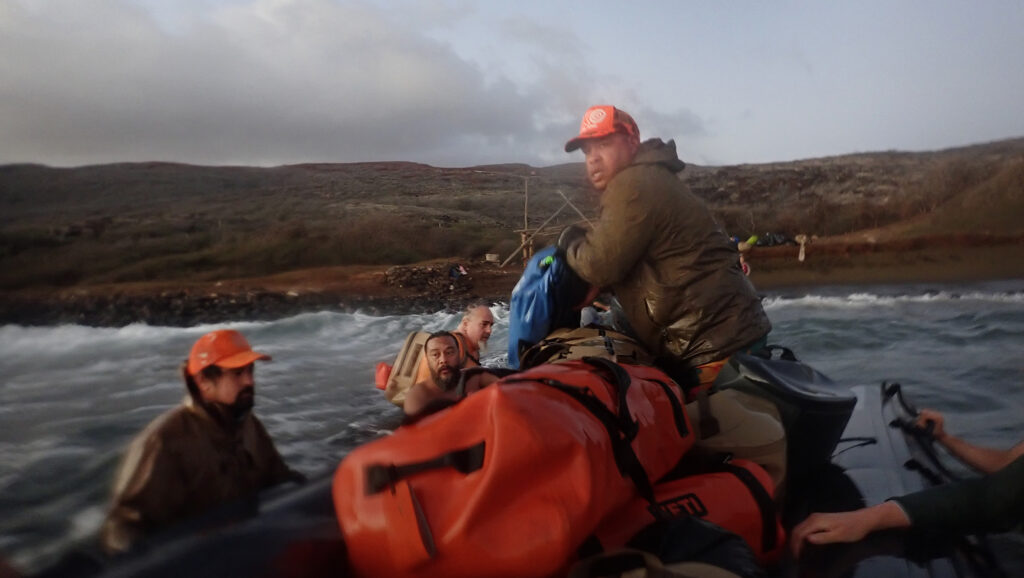 Protect Kahoʻolawe ʻOhana (PKO) CJ Elizares, top, moves ukana (duffel bags, gear) onto the zodiac as the access wraps up Wednesday, Jan. 7, 2026, in Hakioawa. Departing Kahoʻolawe is the reverse from arriving. (Kevin Fujii/Civil Beat/2026)