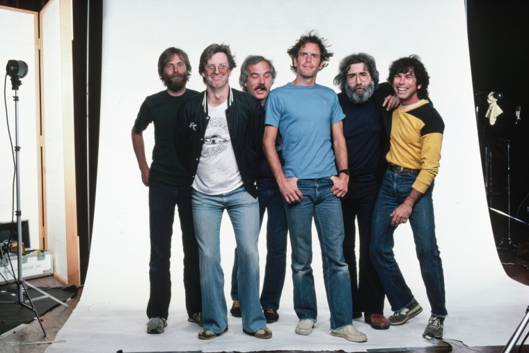 From left, Brent Mydland, Phil Lesh, Bill Kreutzmann, Bob Weir, Jerry Garcia, and Mickey Hart pose on set in front of a white backdrop