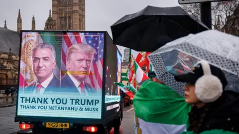 EPA A mobile billboard saying "Thank you Trump" passes by supporters of Reza Pahlavi, the exiled son of Iran's last shah, protesting outside the Houses of Parliament in London on 13 January 2026