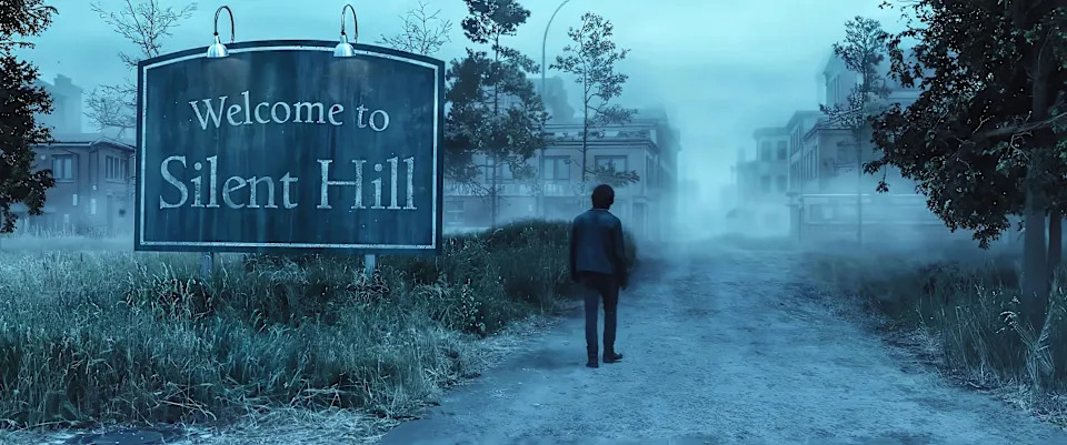  Jeremy Irvine in Return to Silent Hill, A man is walking on a dirt parth as a ghostly fog surrounds him. You can see a large house ahead of him and a sign reading 