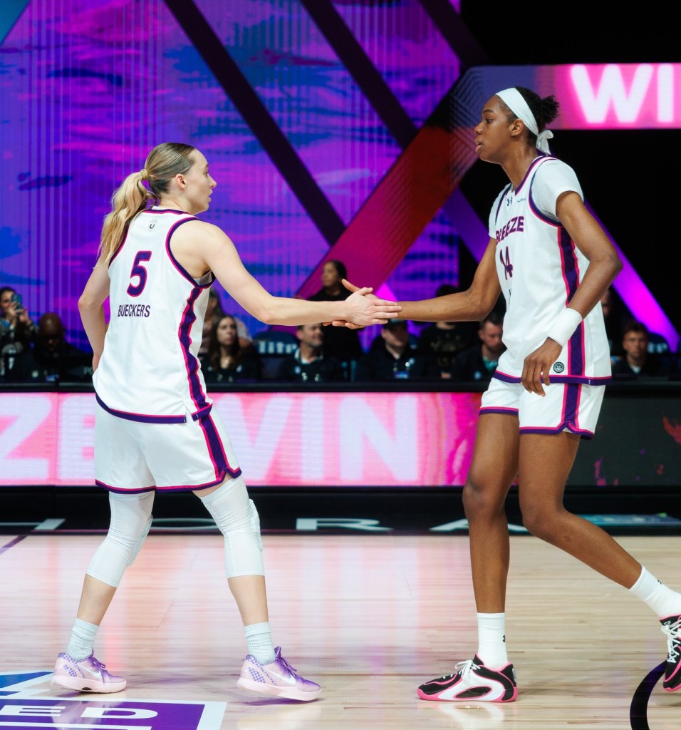 Two players shake hands on the court. Both wear white jerseys. 