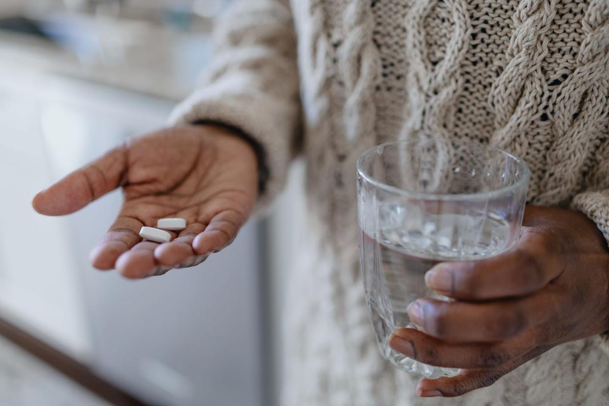 woman holds pills and glass of water