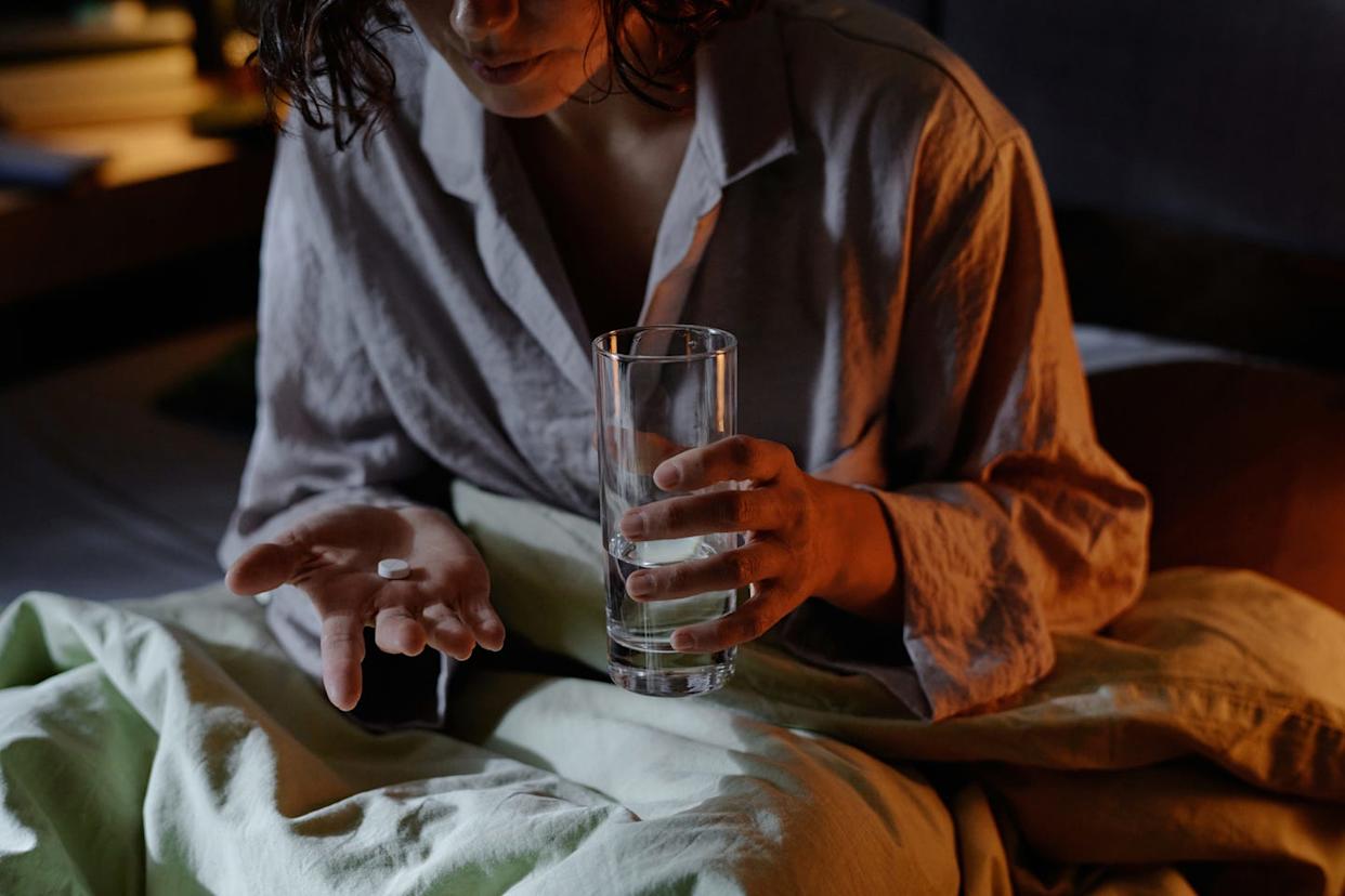vitamins dietitians say not morning medium close up of unrecognizable suffering from insomnia woman sitting in bed holding glass of water and sleeping pill