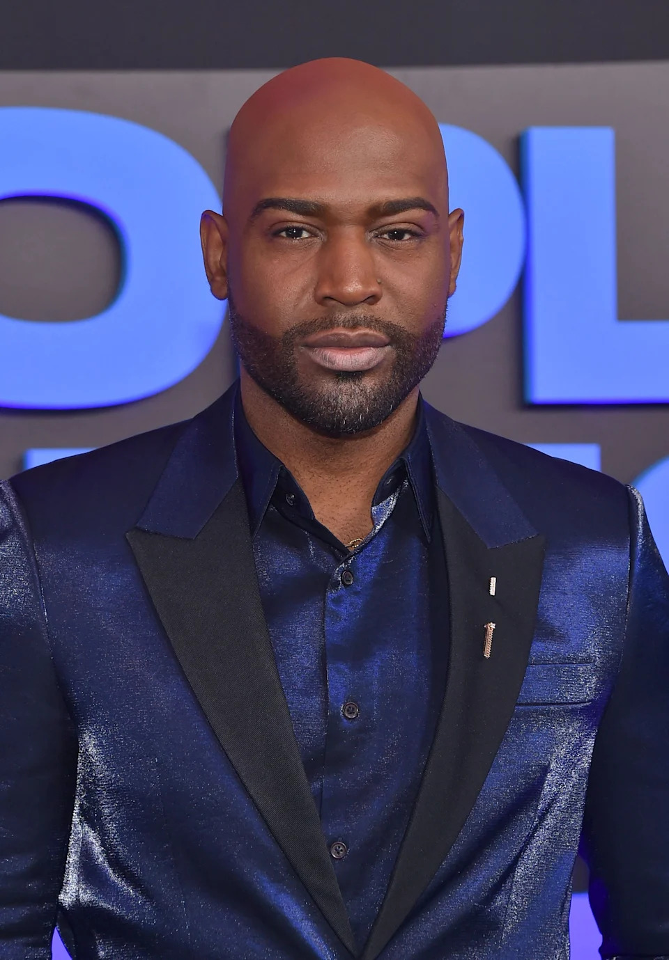 Karamo Brown wearing a shiny suit jacket with satin or silk texture on the red carpet