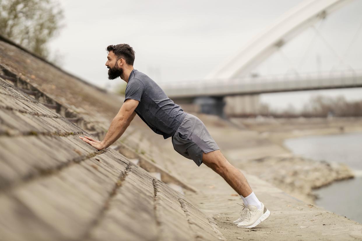 a man exercising outside doing push-ups and planks in the city