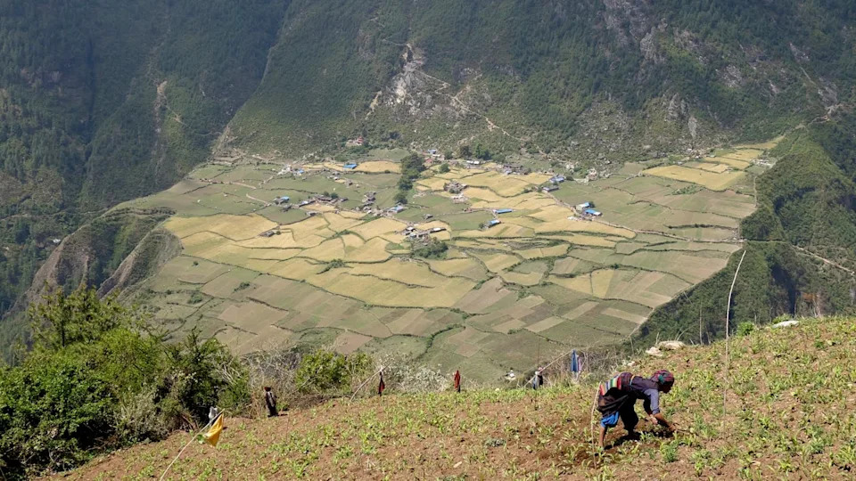 A woman in the foreground bendds over infront of a valley