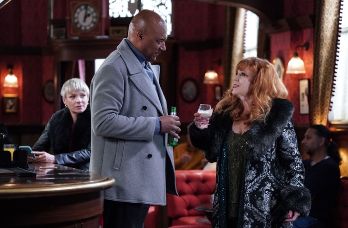 Elaine looks upwards to George in The Queen Vic, as Nicola sits behind in a scene from EastEnders