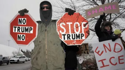 Reuters a protester hold up stop signs with the words "Stop Trump" and "No Trump no"