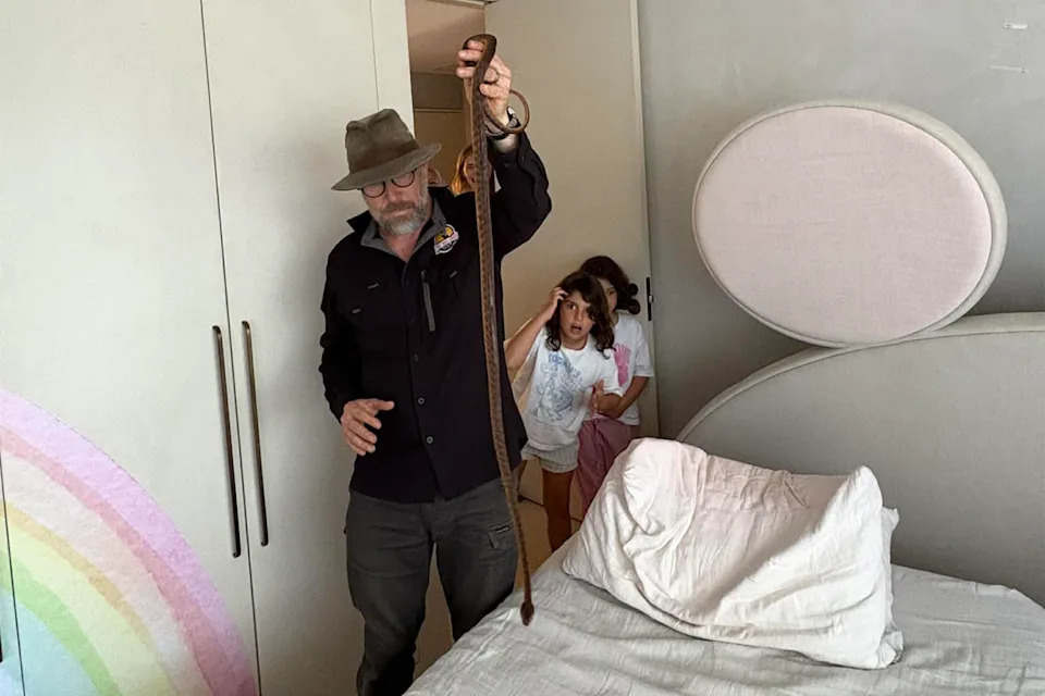 Chris Williams holding the snake in the bedroom as two kids watch.