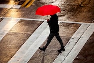 A pedestrian braces against a cold rain while crossing Victory Avenue near the American...
