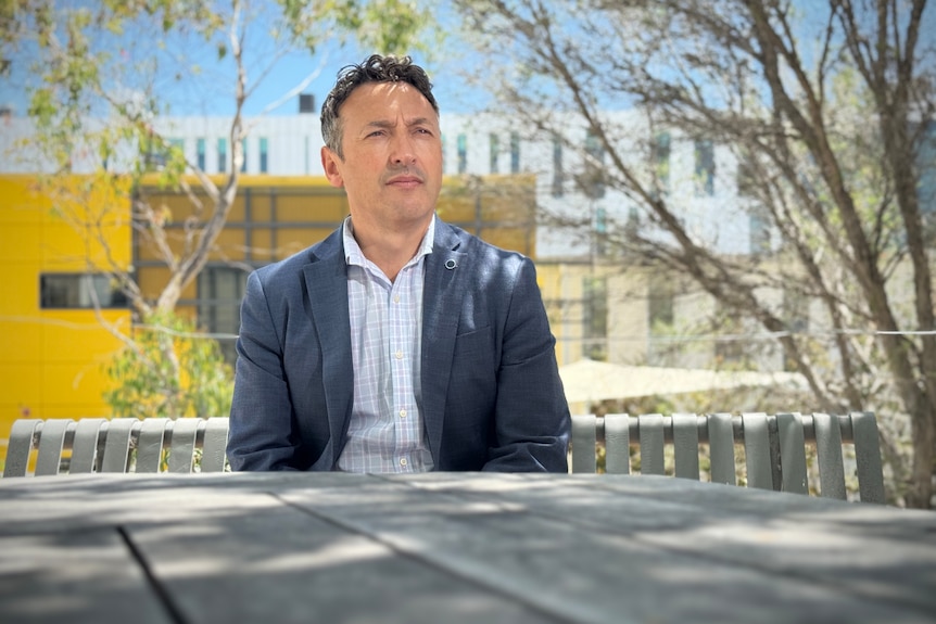 A man in a suit sits on a park bench.