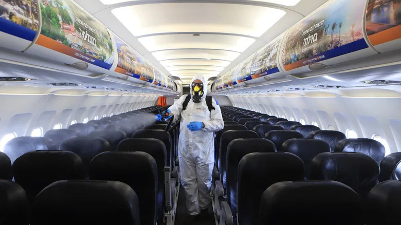 Man in hazmat suit spraying an empty plane