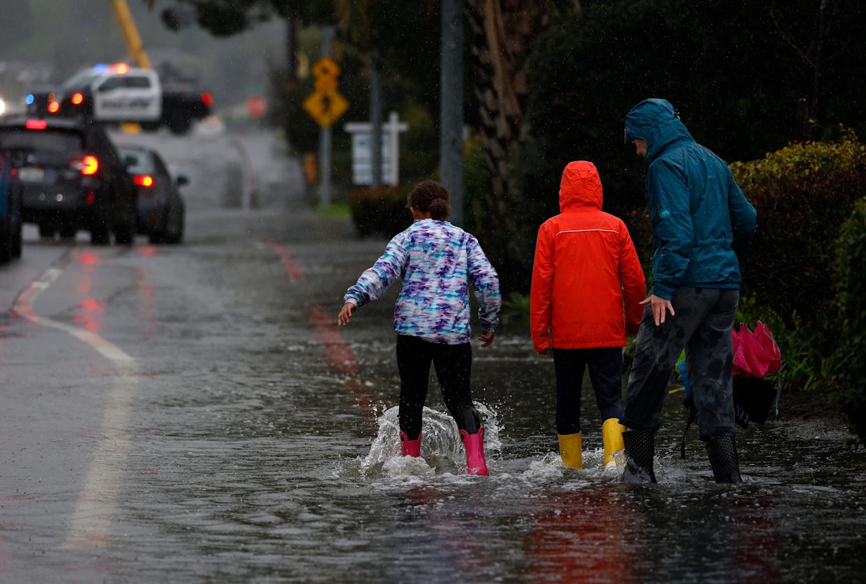 Pedestrians walk through floodwaters on Jan. 5, 2026 in Corte Madera, California, when the San Francisco Bay Area experienced unusually high tides that pushed water into low-lying streets.