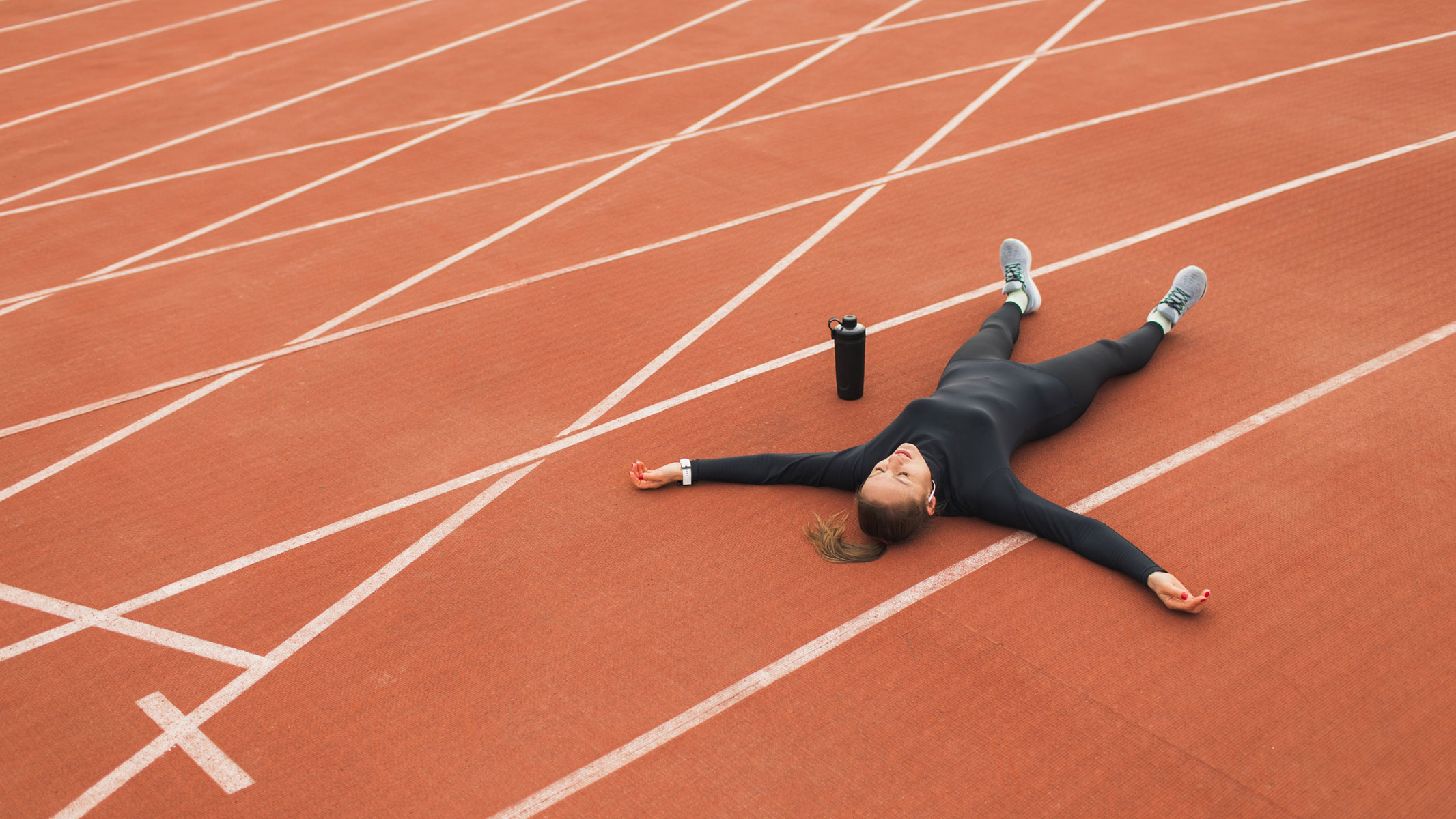 A picture of a young woman lying flat on a running track
