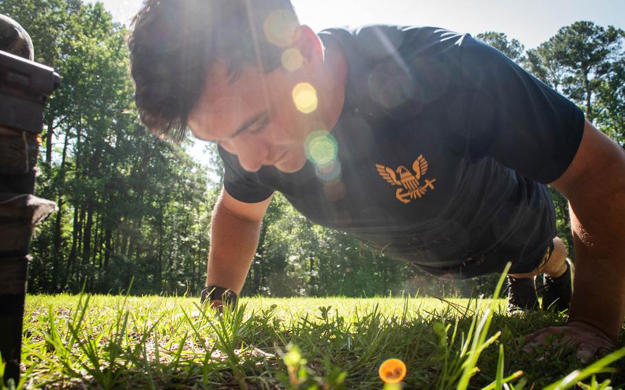 A sailor does pushups in the grass during a competition.