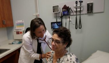 A doctor uses a stethoscope to listen to a patients back during a medical examination in a clinic room.