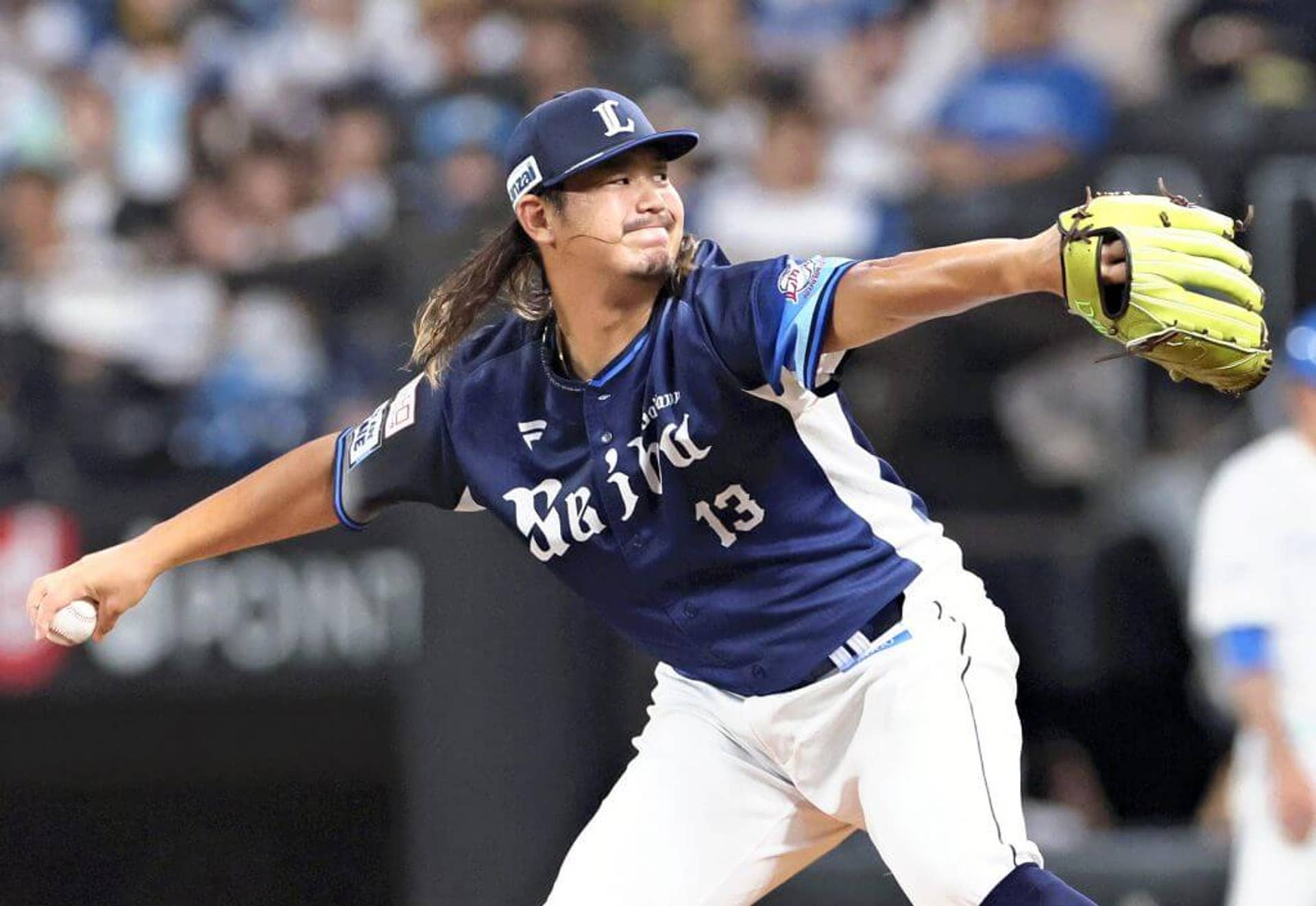 Kona Takahashi holds a baseball in his right hand as he delivers a pitch.