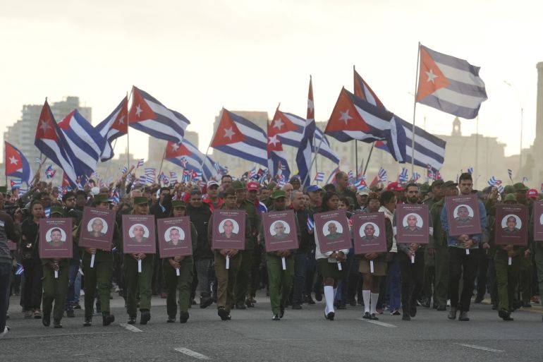 Soldiers carrying photos of Cuban officers killed during the U.S. operation in Venezuela that captured Venezuelan President Nicolas Maduro march the U.S. Embassy in Havana, Cuba, Friday, Jan. 16, 2026. (AP Photo/Ramon Espinosa)