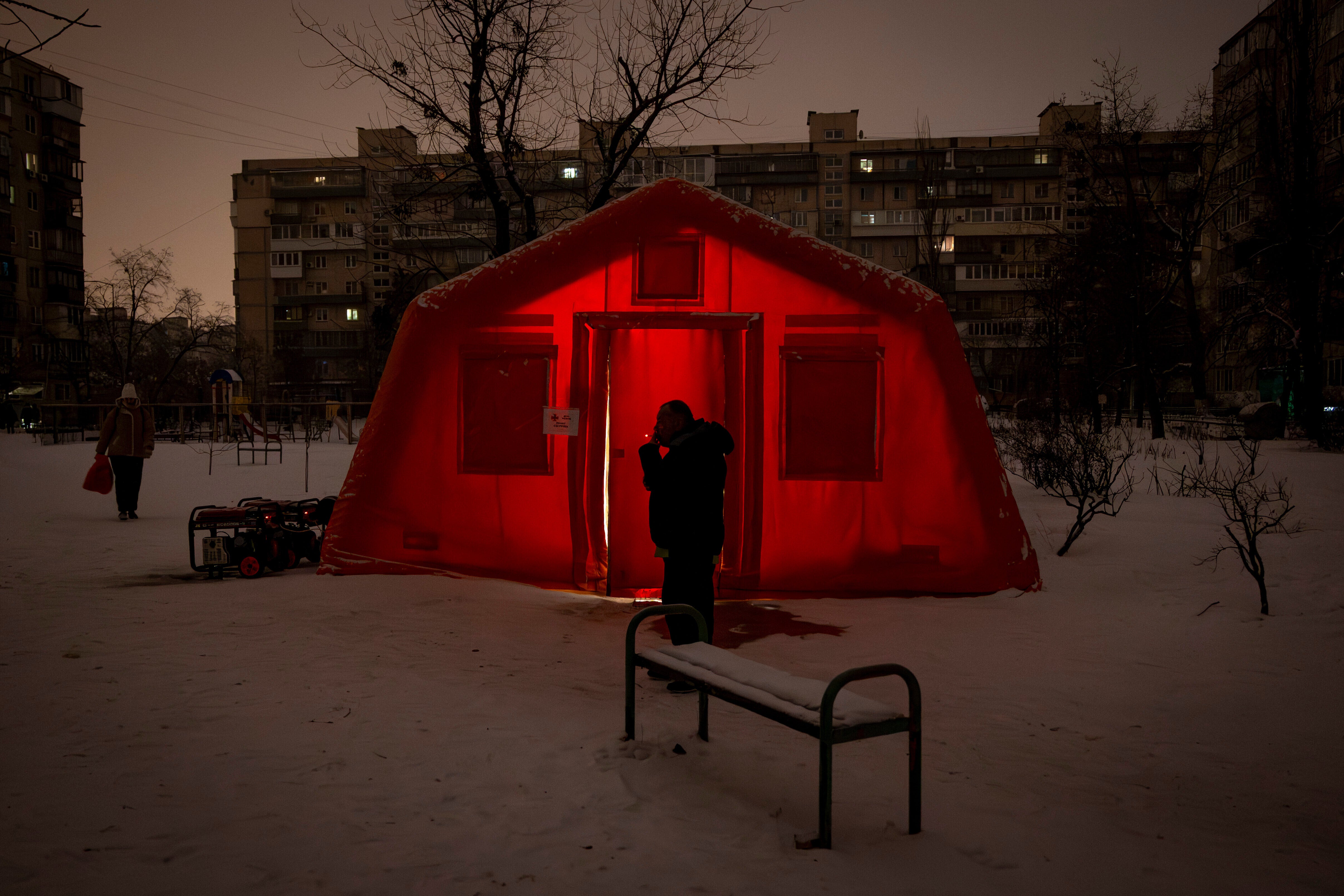 A man sits outside of an emergency tent where people can warm up following Russia's regular air attacks against the country's energy objects, that leave residents without power, water and heating in the dead of winter in Kyiv