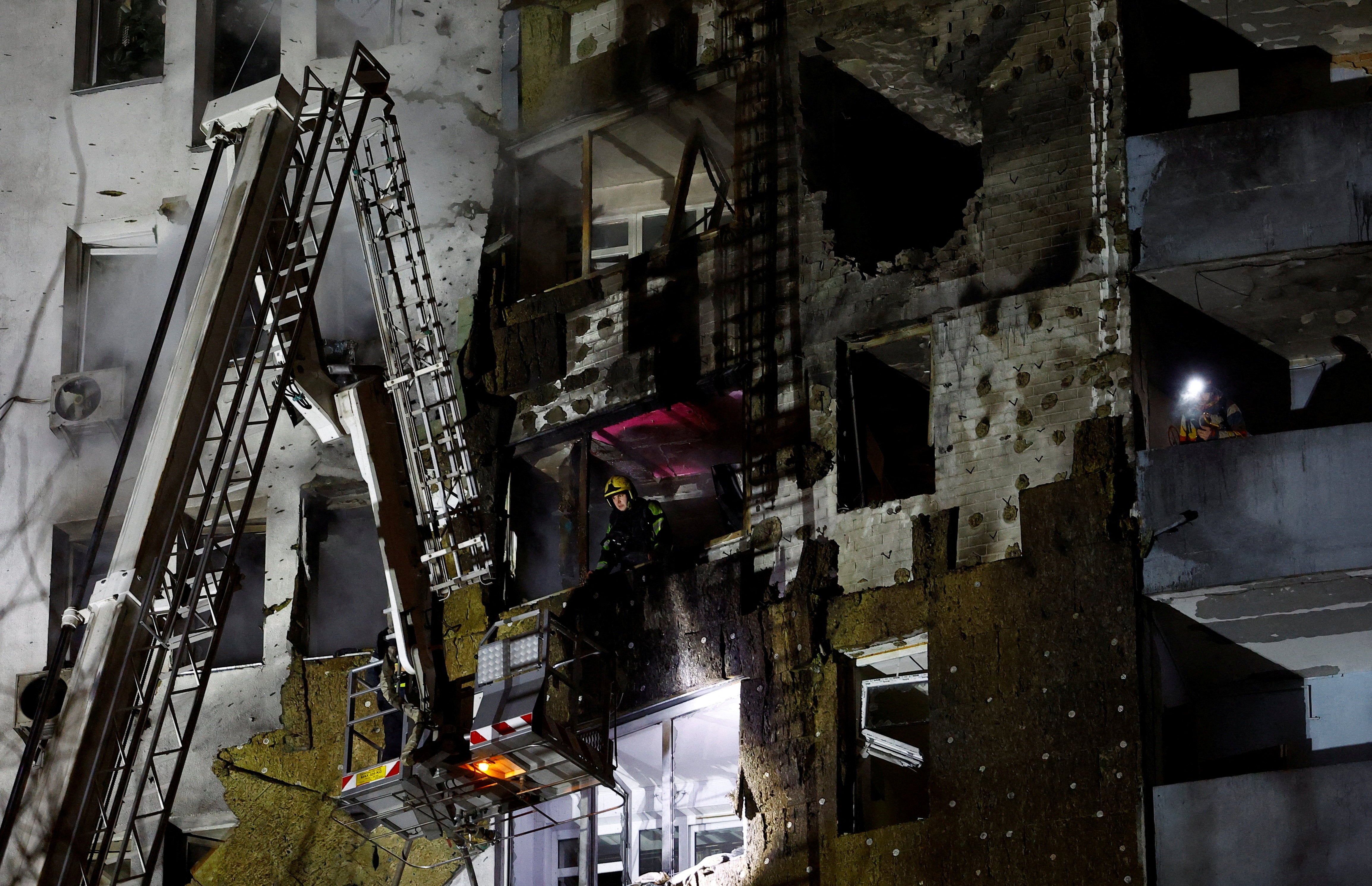 Firefighters work in an apartment building that was hit by a Russian drone strike in Kyiv
