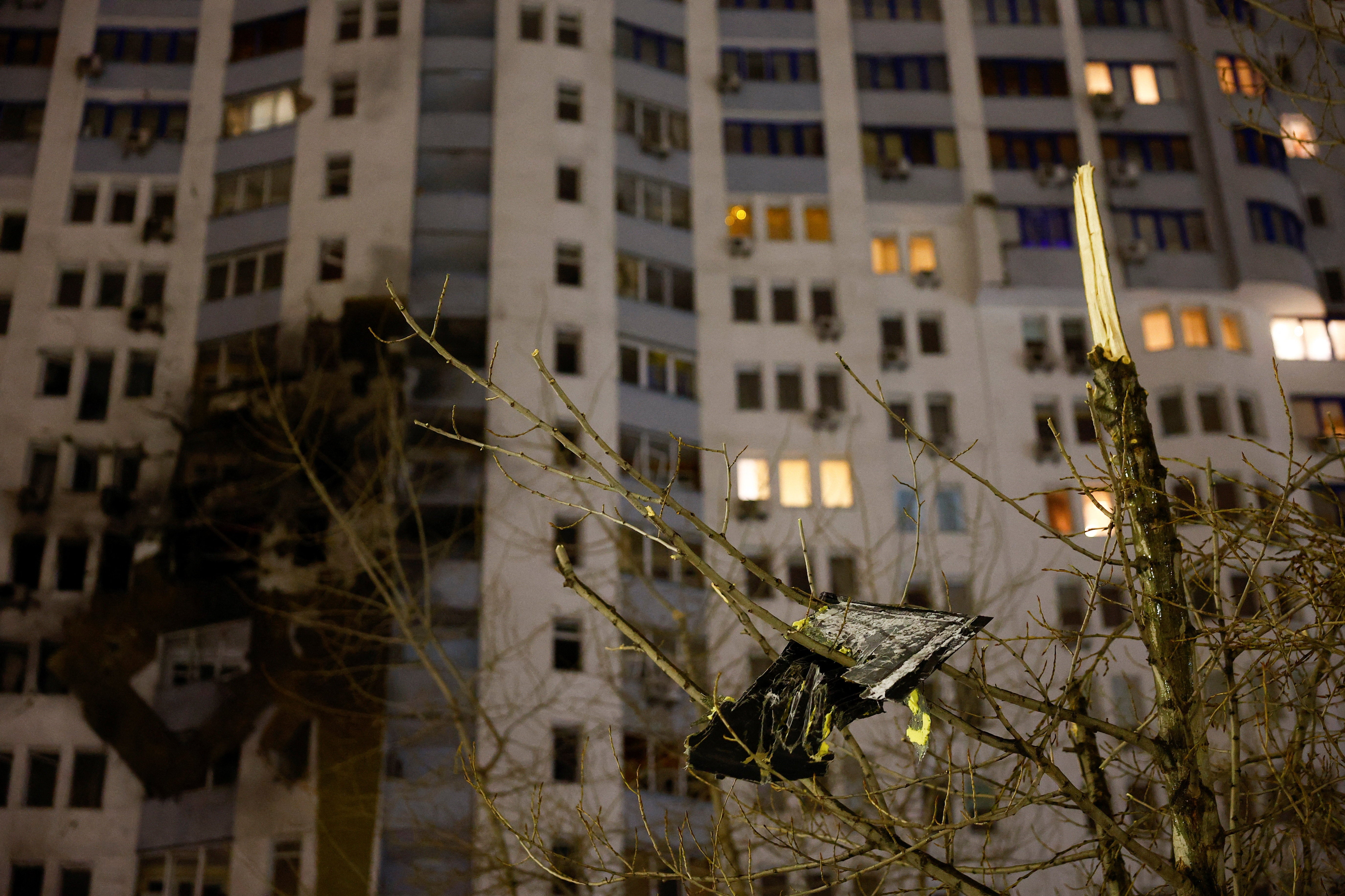 A part of a Russian drone hangs from a damaged tree following a Russian drone strike in Kyiv